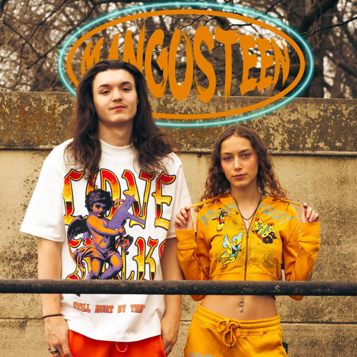Man and woman in graphic streetwear under the Mangosteen neon logo